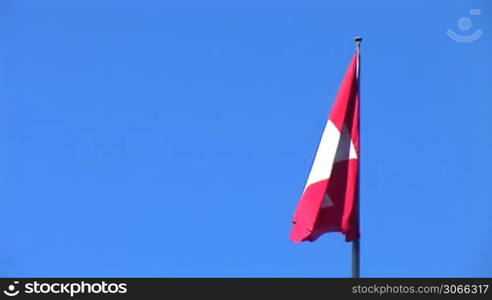 Swiss flag flutters against a blue sky