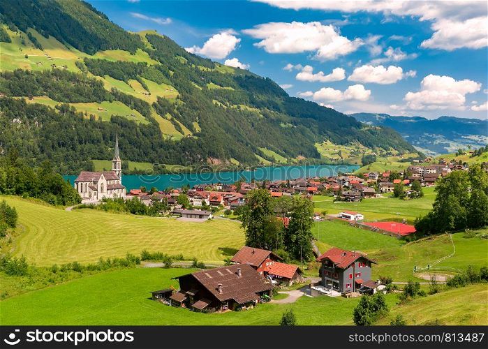 Swiss village Lungern with its traditional houses and Neo-Gothic church along the lake Lungerersee, canton of Obwalden, Switzerland. Zurich, the largest city in Switzerland