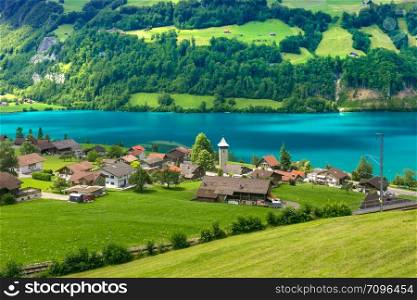 Swiss village Lungern with its traditional houses and old church tower Alter Kirchturm along the lake Lungerersee, canton of Obwalden, Switzerland. Zurich, the largest city in Switzerland