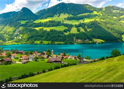 Swiss village Lungern with its traditional houses and old church tower Alter Kirchturm along the lake Lungerersee, canton of Obwalden, Switzerland. Zurich, the largest city in Switzerland
