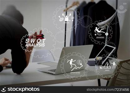 SWOT Analysis virtual diagram with Strengths, weaknesses, threats and opportunities of company.Fashion designer working with mobile phone and using laptop with digital tablet computer in modern studio.