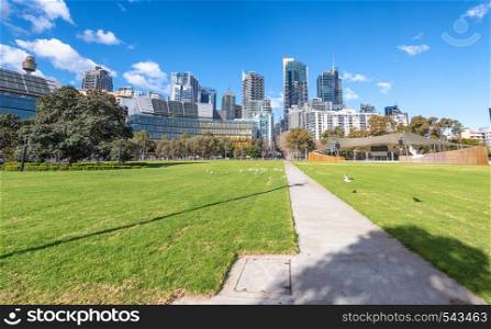 SYDNEY, AUSTRALIA - AUGUST 19, 2018: City skyscrapers from a beautiful park on a sunny day. Sydney attracts 15 million tourists annually.