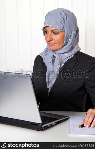 symbolfoto islam. muslim woman wearing a headscarf in an office