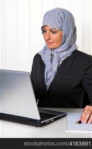 symbolfoto islam. muslim woman wearing a headscarf in an office