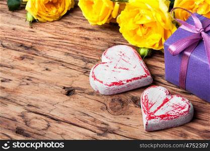 Symbolic wooden heart and flowers. Symbolic hearts, roses and a gift. Valentines Day