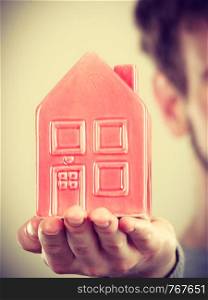 Symbolism housing safety family finances mortgage concept. Young man holding house on palm. Male presenting home model.. Young man holding house on palm.