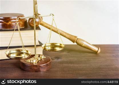 Symbols of law: wood gavel, soundblock, golden scales and two thick old books