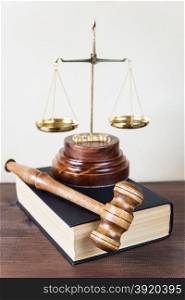 Symbols of law: wood gavel, soundblock, scales and thick old book
