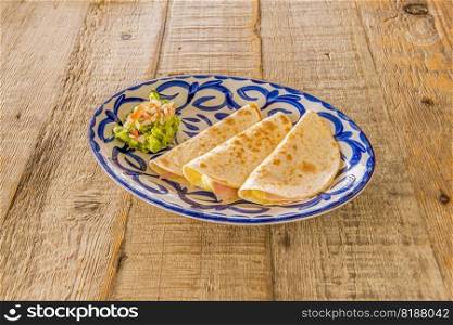 Synchronized, it is frequently confused with Mexican quesadillas. dThey are so called because the two tortillas are  synchronized , covering the content of ham and cheese.
