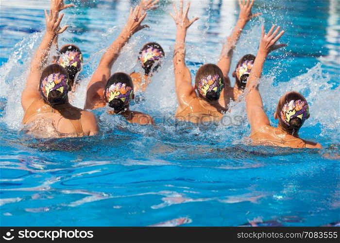 Synchronized swimming team performing a synchronized routine of elaborate moves in the water
