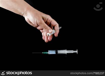 Syringe and pharmaceutical vial in human hands
