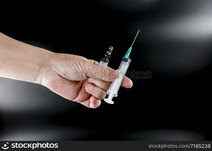 Syringe and pharmaceutical vial in human hands