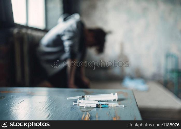 Syringe and spoon for dose preparing on the table, drug addict catches the buzz after injection on background. Addiction concept, addicted people. Syringe and spoon for dose preparing on the table