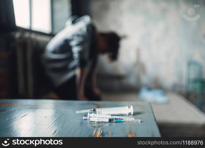 Syringe and spoon for dose preparing on the table, drug addict catches the buzz after injection on background. Addiction concept, addicted people. Syringe and spoon for dose preparing on the table