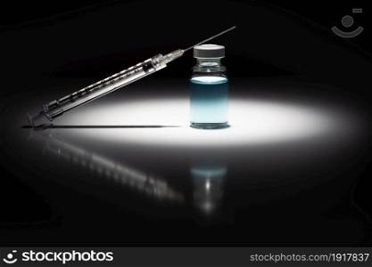 Syringe Needle and Medicine Vial With Light Blue Chemical Spot Lit on Reflective Background.
