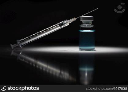 Syringe Needle and Medicine Vial With Light Blue Chemical Spot Lit on Reflective Background.