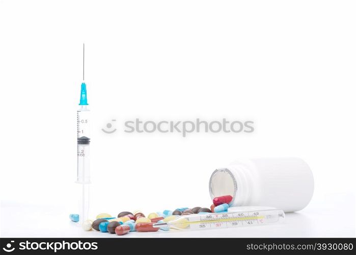 Syringe, pills bottle, thermometer and colorful capsules on white background