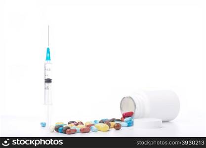 Syringe, plastic white bottle and various pills on white background