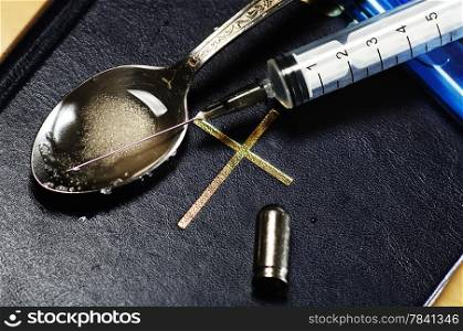 syringe, spoon ,bullet and lighter on the Bible