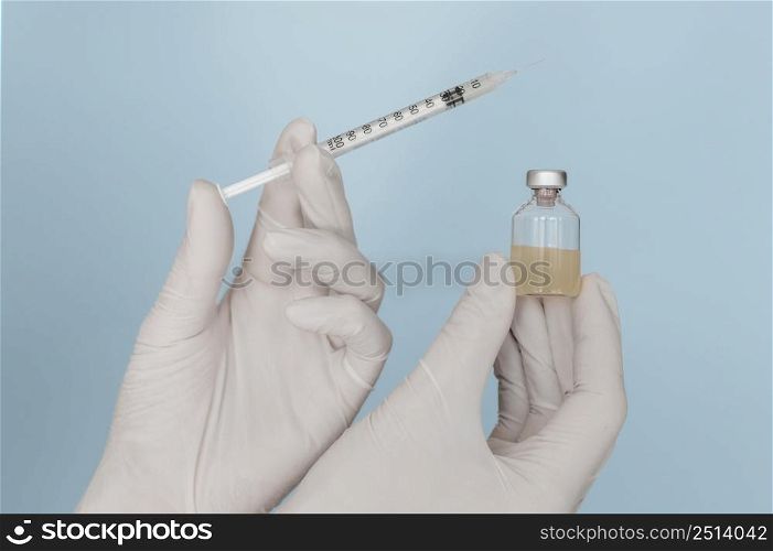 syringe vaccine bottle hands wearing gloves