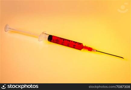 Syringe with blood closeup on orange background. Syringe with blood on orange background