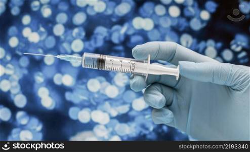 syringe with vaccine held by hand with glove