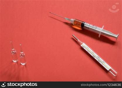 Syringes and ampoules on red background.