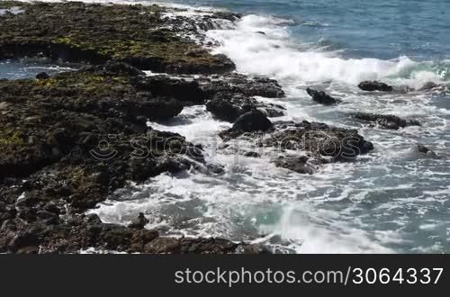 Szene zeigt einen steinigen Strand mit starken Wellen. Scene shows a rocky beach with strong waves.