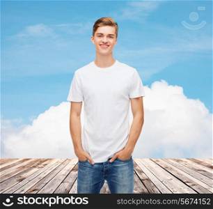 t-shirt design, advertising, vacation and people concept - smiling young man in blank white t-shirt over wooden berth and blue sky background