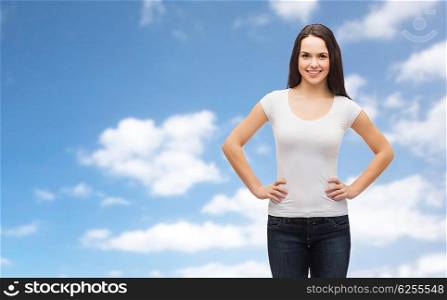 t-shirt design and people concept - smiling young woman in blank white t-shirt over blue sky and clouds background. smiling young woman in blank white t-shirt