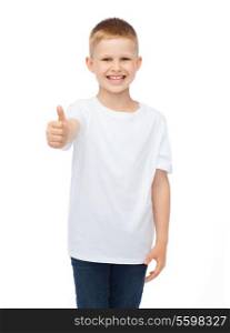 t-shirt design, childhood and happy people concept - smiling little boy in blank white t-shirt showing thumbs up