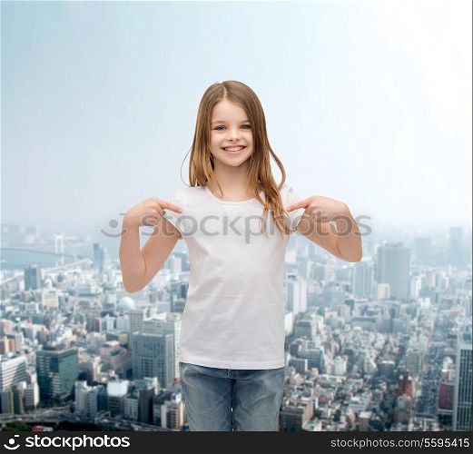 t-shirt design concept - smiling little girl in blank white t-shirt pointing at herself
