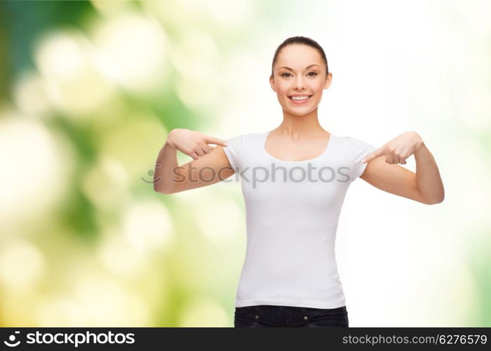 t-shirt design concept - smiling woman in blank white t-shirt pointing at herself