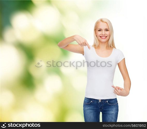 t-shirt design concept - smiling young woman pointing finger to blank white t-shirt