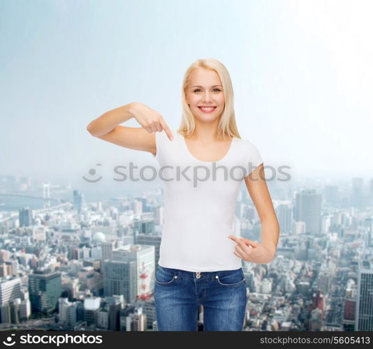 t-shirt design concept - smiling young woman pointing finger to blank white t-shirt