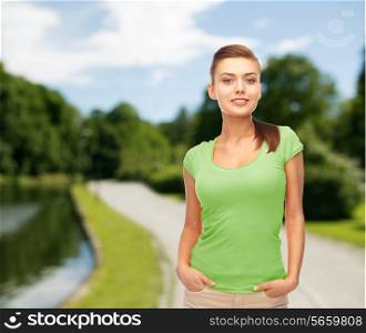 t-shirt design, leisure and people concept - smiling young woman in blank green t-shirt