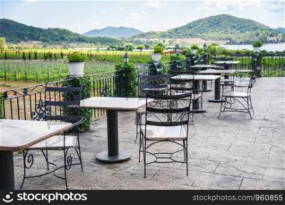 table and chairs in the balcony of outdoor restaurant view nature farm and mountain background / Dining table on the terrace
