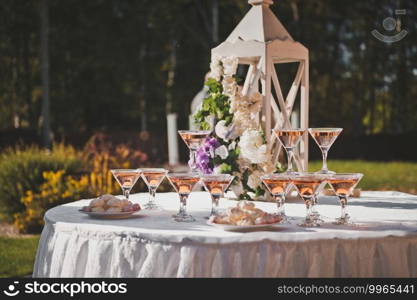 Table for guests with pyramids of ch&agne glasses.. Summer table with snacks for guests at the wedding 2245.