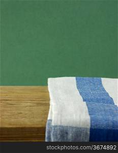 Table-napkin and old wooden deck table with green grunge background