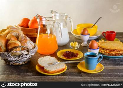 table of breakfast full set with eggs, pancakes, bread, jam ,juice and more