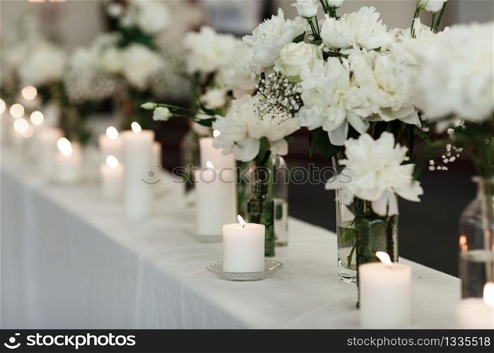 Table setting at wedding reception. Floral compositions with beautiful flowers and greenery, candles on decorated table. Coziness and style. Modern event design. selective focus. Table setting at wedding reception. Floral compositions with beautiful flowers and greenery, candles on decorated table. Coziness and style. Modern event design. selective focus.