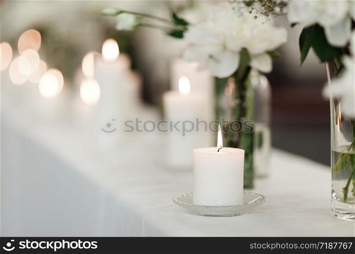 Table setting at wedding reception. Floral compositions with beautiful flowers and greenery, candles on decorated table. Coziness and style. Modern event design. selective focus. Table setting at wedding reception. Floral compositions with beautiful flowers and greenery, candles on decorated table. Coziness and style. Modern event design. selective focus.