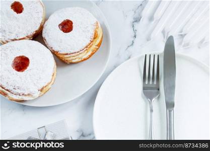 Table setting for Hanukkah Jewish holiday. Plate and cutlery on a white background. Candles, gifts and dessert donut sufganiyot.. Table setting for Hanukkah Jewish holiday. Plate and cutlery on white background. Candles, gifts and dessert donut sufganiyot.