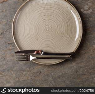 Table setting. plate, knife and fork on stone background. Plate, knife and fork on stone background