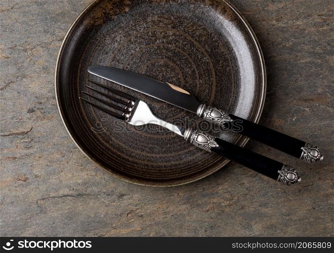 Table setting. plate, knife and fork on stone background. Plate, knife and fork on stone background