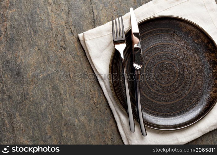 Table setting. plate, knife and fork on stone background. Plate, knife and fork on stone background