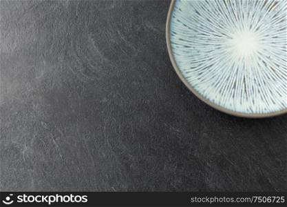 table setting, tableware and eating concept - close up of blue ceramic plate on slate background. close up of blue ceramic plate on slate background