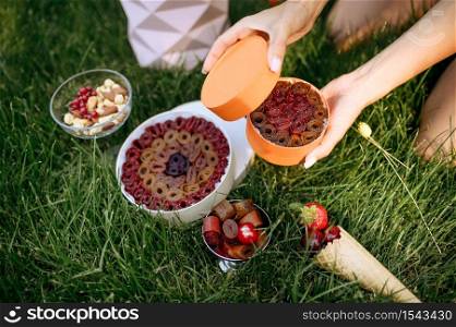 Table setting, tea party decoration, woman opened boxes with berries. Luxury tableware, restaurant outdoors. Wedding celebration on summer meadow. Tea party, woman opened boxes with berries