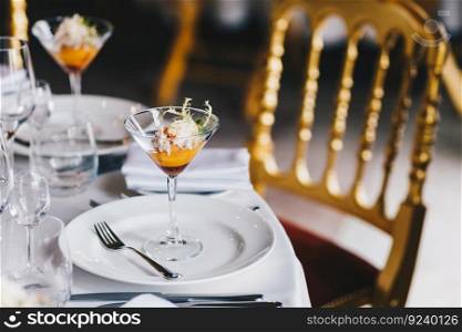Table setting with beautifully decoration, tasty cocktail and white cutlery for festive event. Luxury resturant with no people. Wedding reception. Dinner set up. Cozy atmopshere.