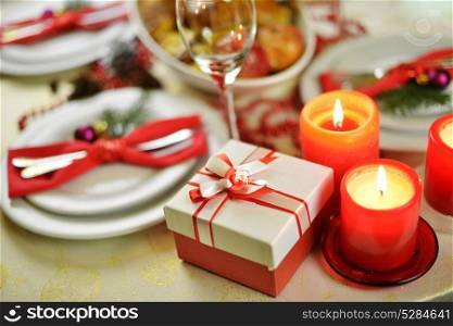 table setting with candles. fork, knife and red napkin on dish